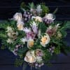 Bouquet of cream roses with purple accents and green foliage