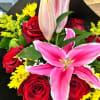 Bouquet of pink lilies, red roses, and yellow daisies wrapped in black and white paper