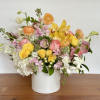 Mixed bouquet of yellow, pink, and white flowers in a white vase