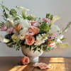 Pastel floral arrangement in a white vase with roses and calla lilies