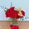 Red roses and pale orchids arranged in a clear glass vase