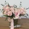 Pink roses arranged in a clear glass vase with a pink ribbon