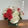 Red roses and white hydrangeas in a square glass vase
