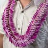 Purple and white orchid petal lei draped around a person’s neck