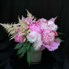Pink floral arrangement in a white vase with feathery white accents