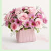 Soft pink roses mingle with purple daisy-like blooms and tiny white filler