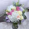 A lush cluster of white hydrangeas anchors this pastel bouquet, creating a