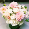 Pink and white flowers arranged in a green glass vase