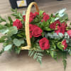 Low wicker basket arrangement of red roses with abundant foliage