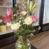 Mixed bouquet of pink and white roses with lilies and other flowers in a clear glass vase