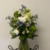 Bouquet of white, green, and blue flowers in a clear glass vase