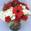 Red gerbera daisies, roses, and white hydrangeas in a glass vase