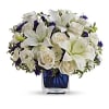 White lilies and roses arranged in a blue glass vase
