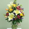 Big white lilies rise above sunny yellow roses and pink alstroemeria in