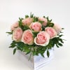 Pink roses arranged in a white wooden box with greenery