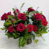 Red roses and carnations in a glass vase with mixed greenery