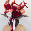 Bouquet of red, pink, and white roses in black wrap with ribbon