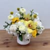 White and yellow floral arrangement in a white vase