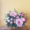 Pink gerbera daisies and roses in a low gold vase