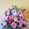 Pink roses and lilies arranged around a heart-shaped angel plaque