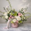 Pink and white floral arrangement in a blush vase with ribbon