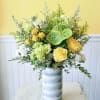 Yellow roses and white blooms in a tall striped vase