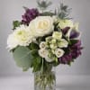 A large ivory rose anchored among white chrysanthemums and a purple-and-white calla