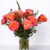 Orange-pink roses arranged in a clear glass vase