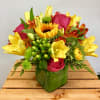 Bright mixed bouquet with sunflowers, yellow lilies, and pink roses in a green vase