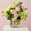 Pink roses and green hydrangeas in a clear glass vase