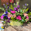 Mixed bouquet in a pale yellow basket with a small bunny figurine beside it