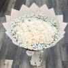 Bouquet of cream roses with white baby's breath in pale wrapping
