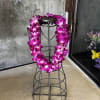 Magenta orchid lei draped over a black metal stand