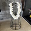 White orchid lei draped over a black metal stand