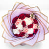 Bouquet of red roses, pink carnations, and white blooms wrapped in lavender paper