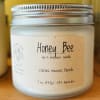 A frosted jar candle with a silver lid and Honey Bee label