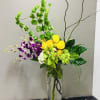 Sunlit yellow roses paired with vibrant purple orchids create a bold, celebratory