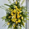 Tall yellow and white floral standing spray on a black easel