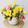 Yellow and pink mixed flowers arranged in a ribbed blue vase