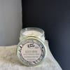 Glass jar candle with a labeled lid on a tabletop