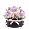 Pink and lavender roses in a black hat box with a pink ribbon