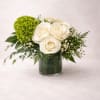 White roses and a green hydrangea in a glass vase