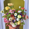 A whimsical garden-style arrangement packed with spring blooms in a colorful palette.