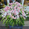 Large pink floral arrangement with roses and orchids in a stand