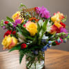 A vibrant, medium-sized birthday arrangement featuring premium yellow roses, pink daisies, white