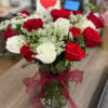 Red and white roses in a glass vase with a red ribbon