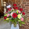 A clustered dozen mixed bouquet of roses, carnations and lilies that reads