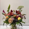 A beautiful floral arrangement featuring a mix of flowers in sunset hues