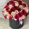 Bouquet of red and blush roses in a black hat box with a pink ribbon