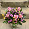 A cheerful mix of pink roses, sunny yellow buds, and playful purple